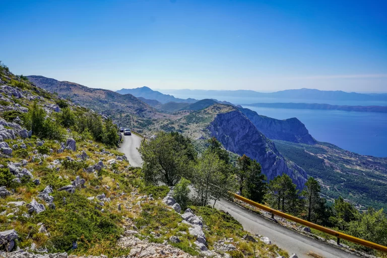 a road overlooking the hillside with the view of the sea in the background